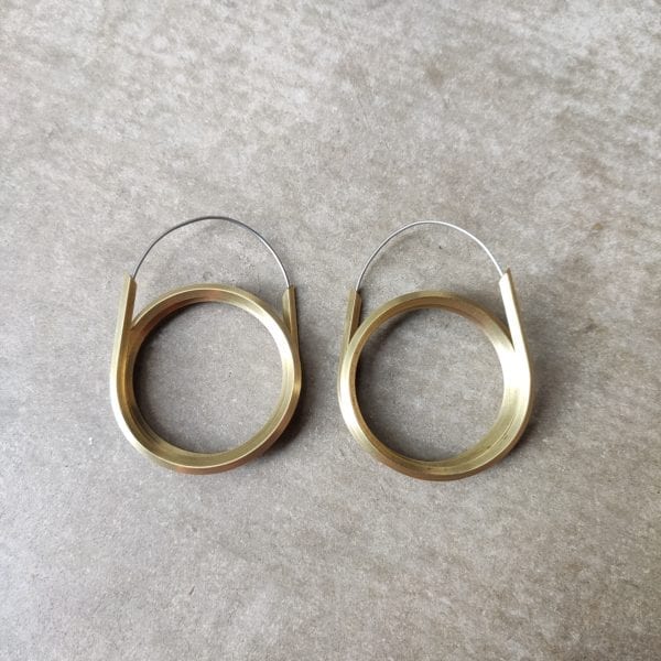 Double coiled brass hoops on soft grey background