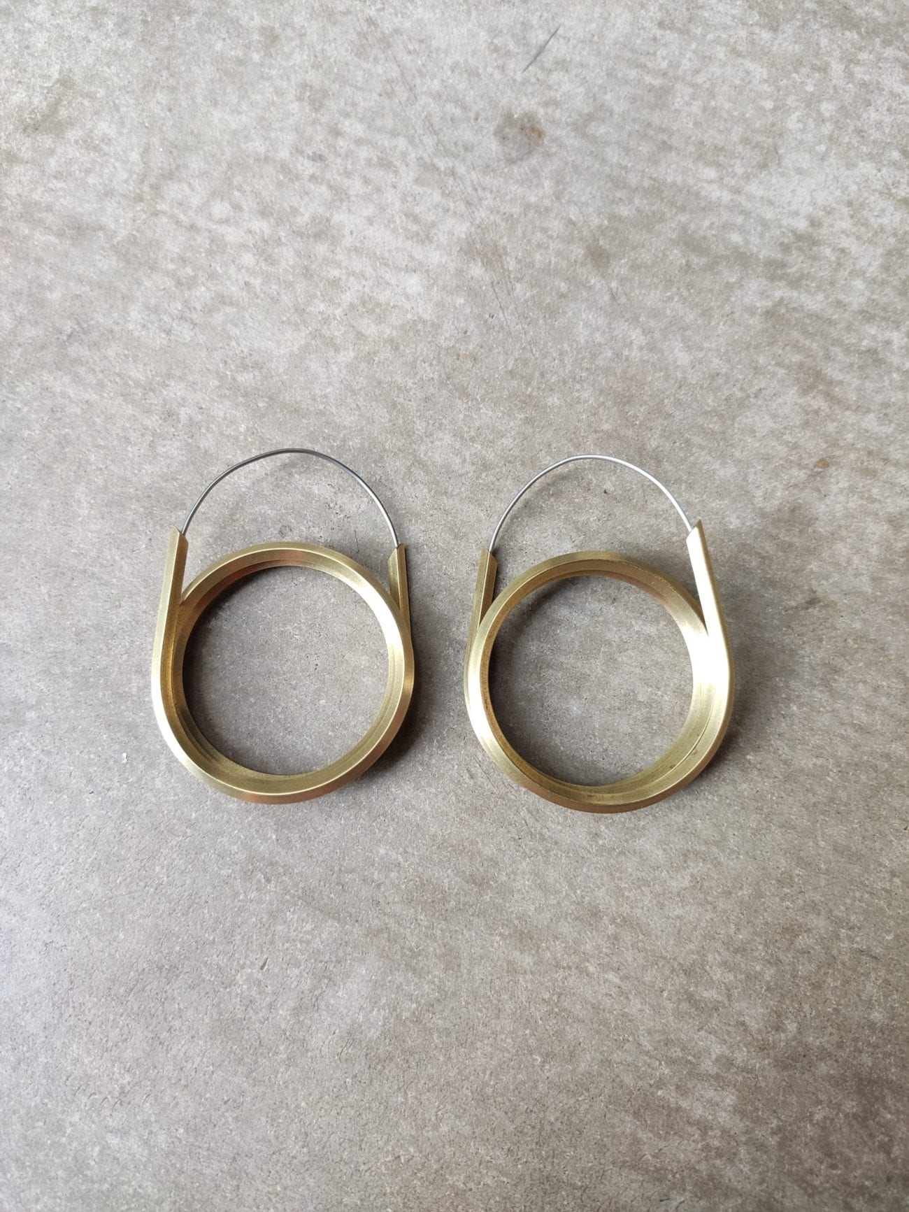 Double coiled brass hoops on soft grey background