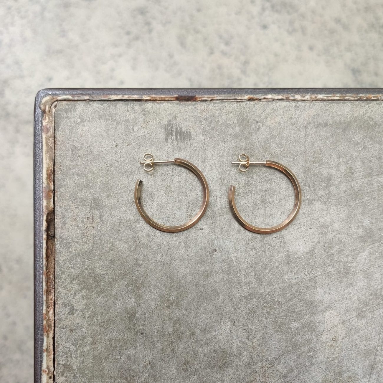 Stud yellow gold hoop on concrete grey background