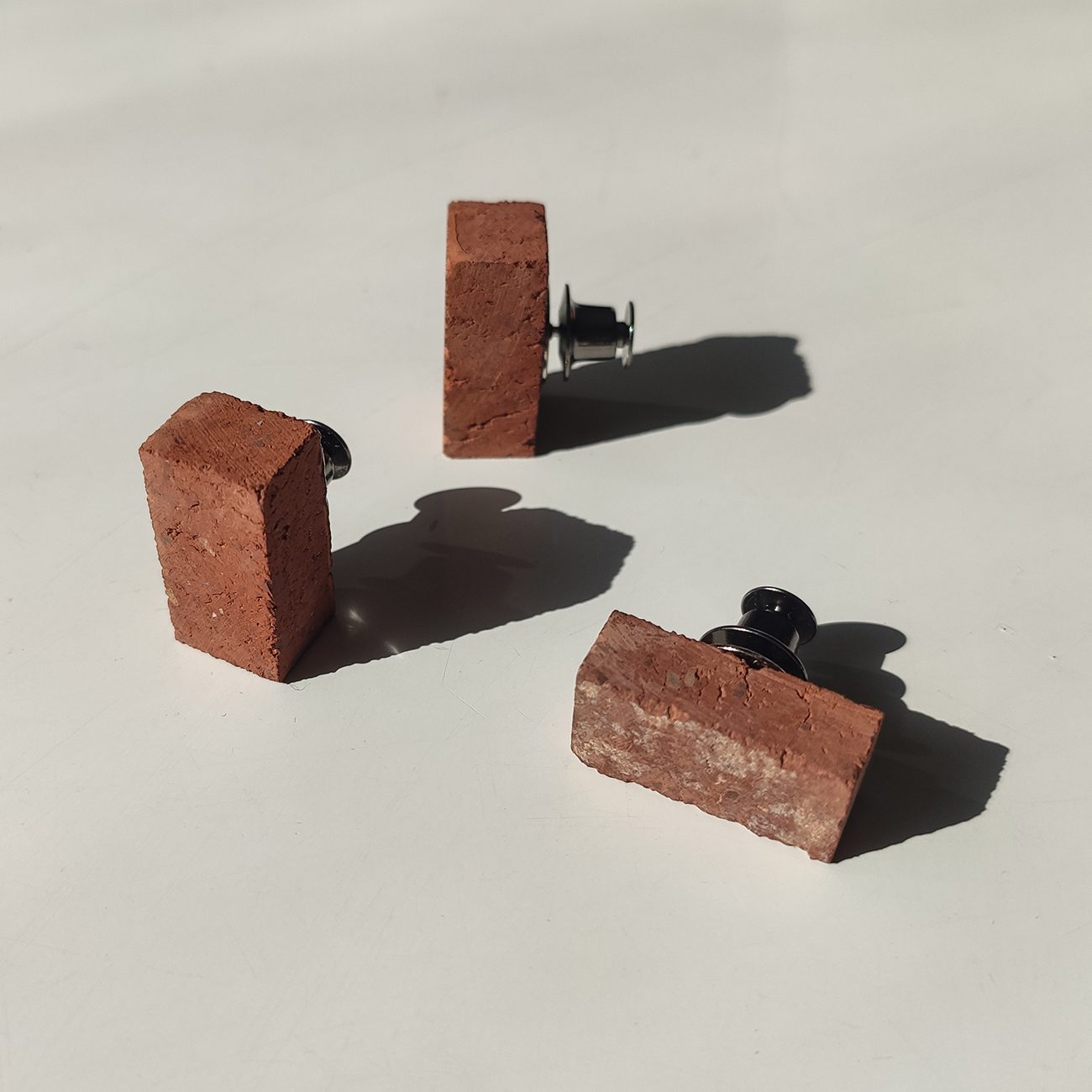 3 little red brick pins on an off white background